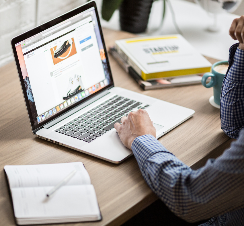 A man is typing on a laptop while sitting at a desk