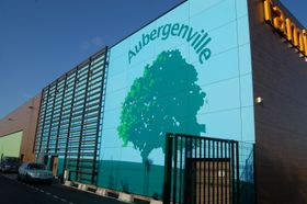 Ein Gebäude, auf dessen Seite ein Baum mit der Aufschrift „Aubergenville“ gemalt ist