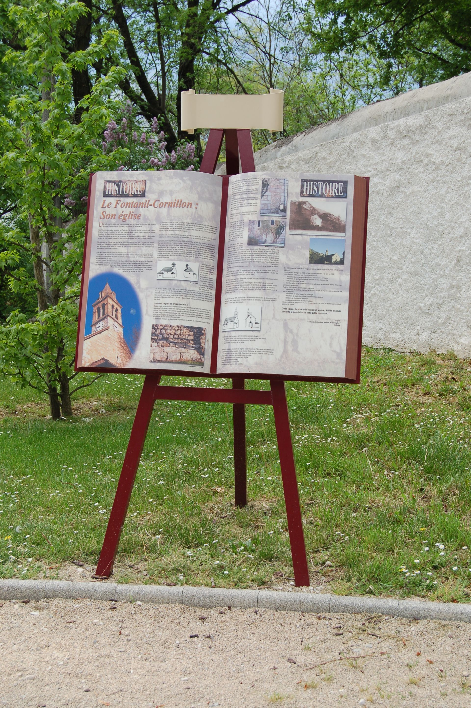 In einem Park liegt ein aufgeschlagenes Buch auf einer hölzernen Staffelei.