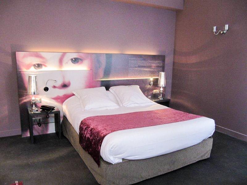 Ein Hotelzimmer mit einem Bett und einem Bild eines Frauengesichts am Kopfende