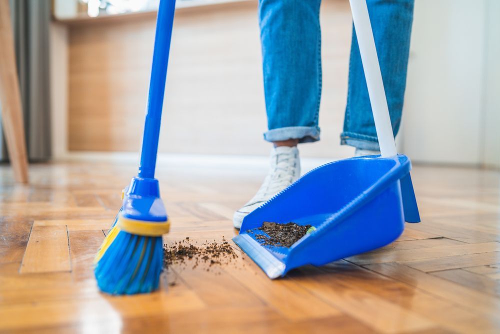 A person is sweeping the floor with a broom and dustpan.