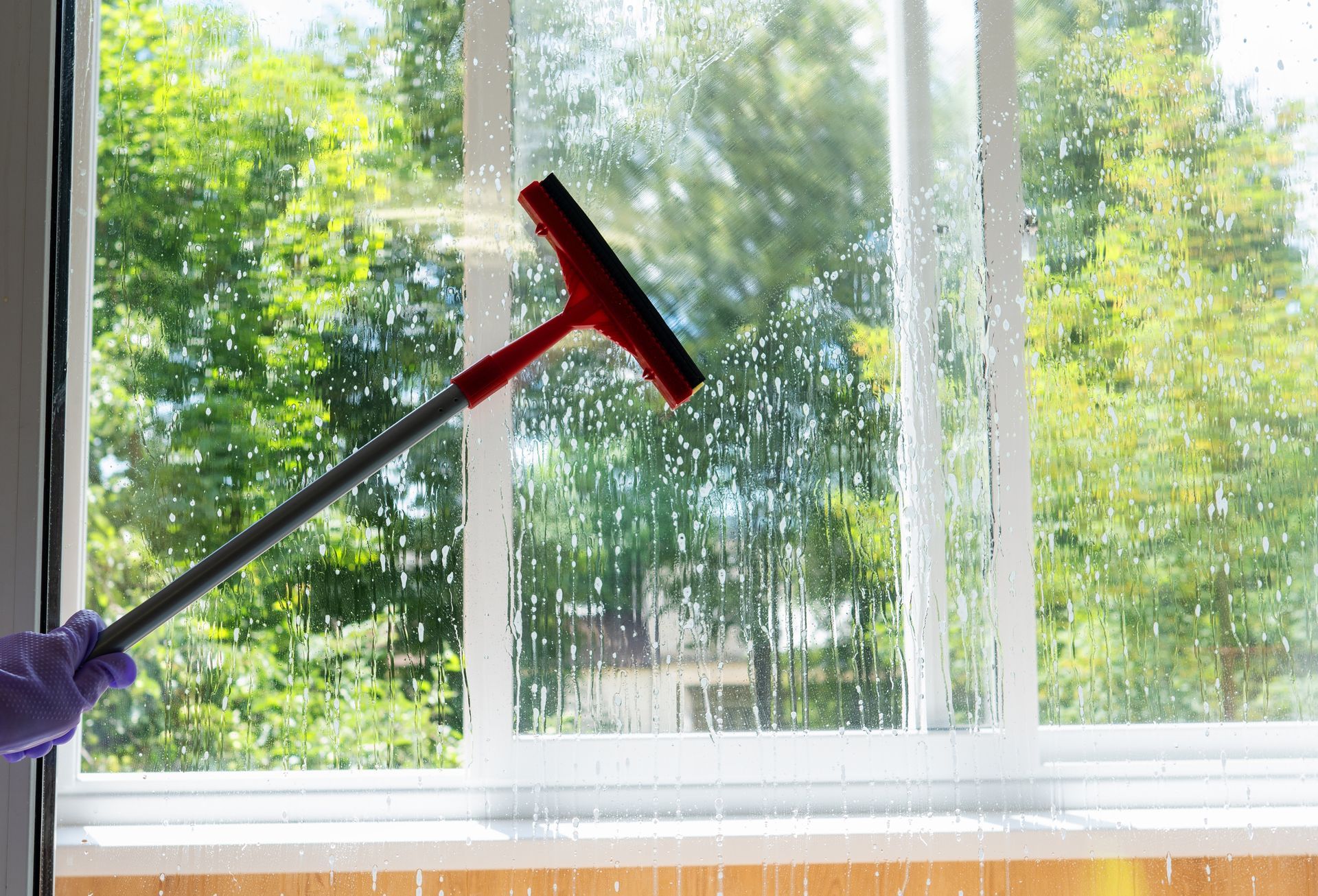 A person is cleaning a window with a squeegee.