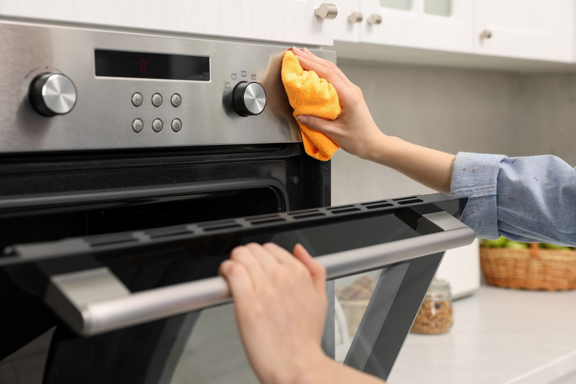 A person is cleaning an oven with a cloth in a kitchen.