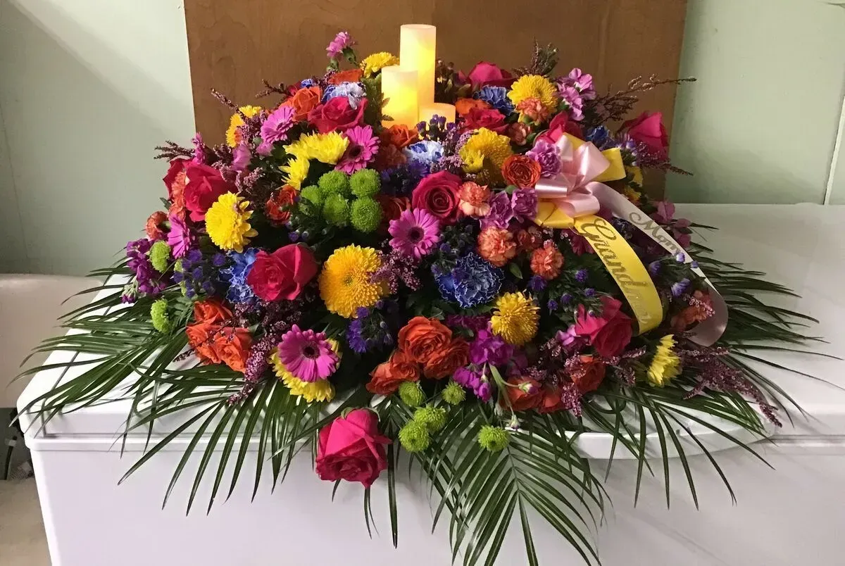 Colorful floral arrangement with candle on white surface.