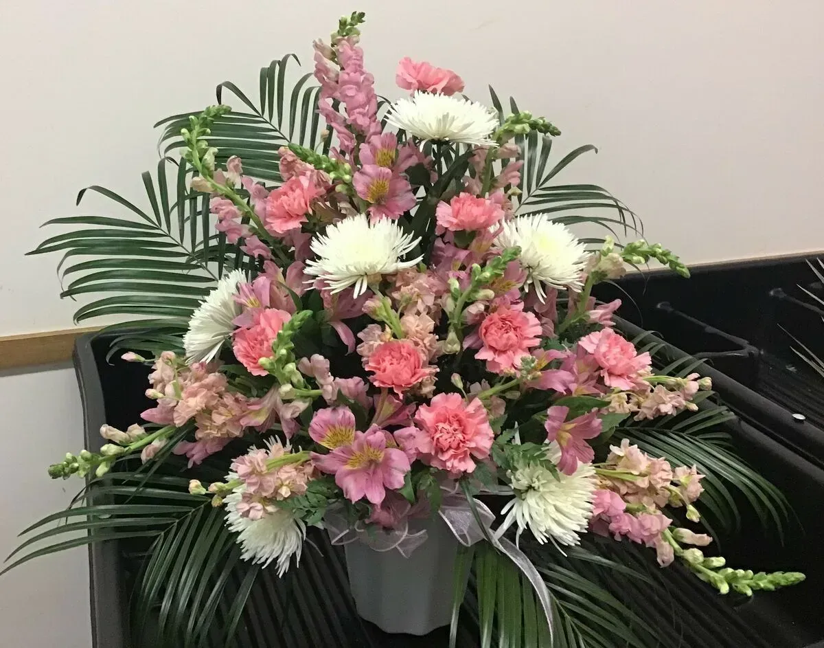 Floral arrangement with pink, white, and green flowers in a gray vase.