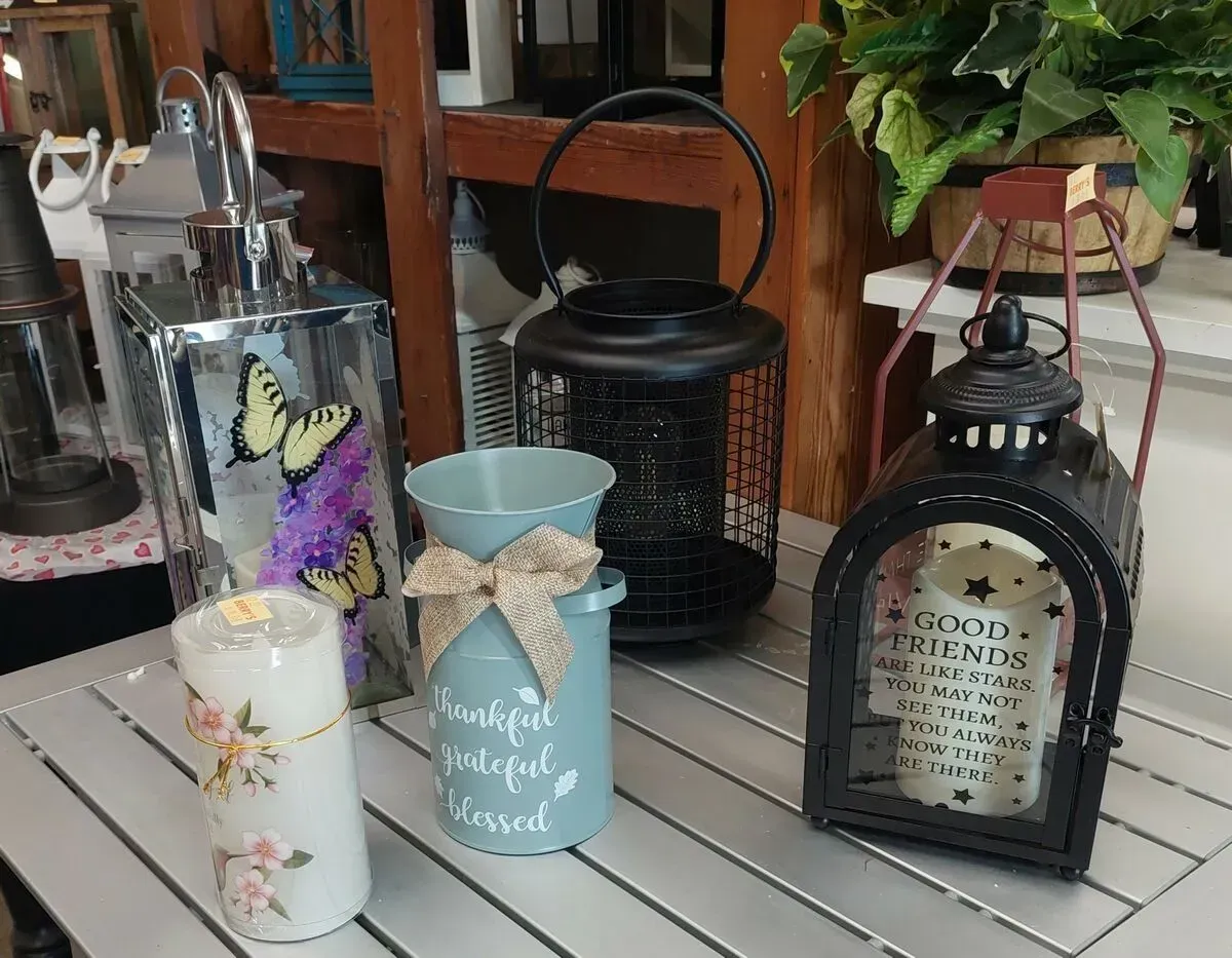 Assortment of decorative lanterns, a candle, and a vase, displayed on a shelf.