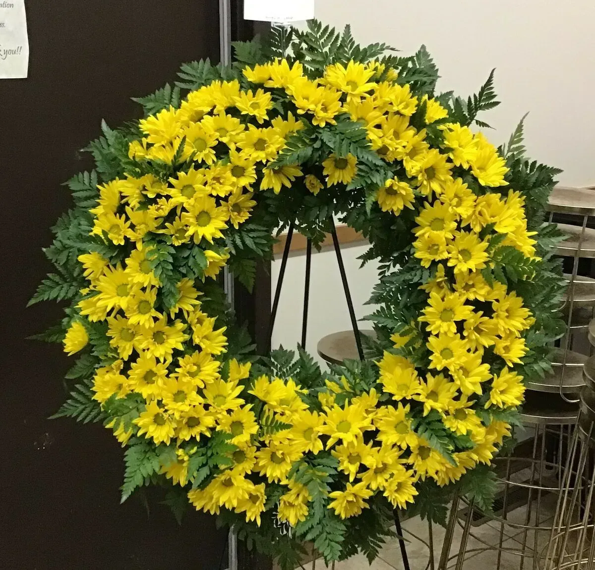 Yellow chrysanthemum wreath on a stand.