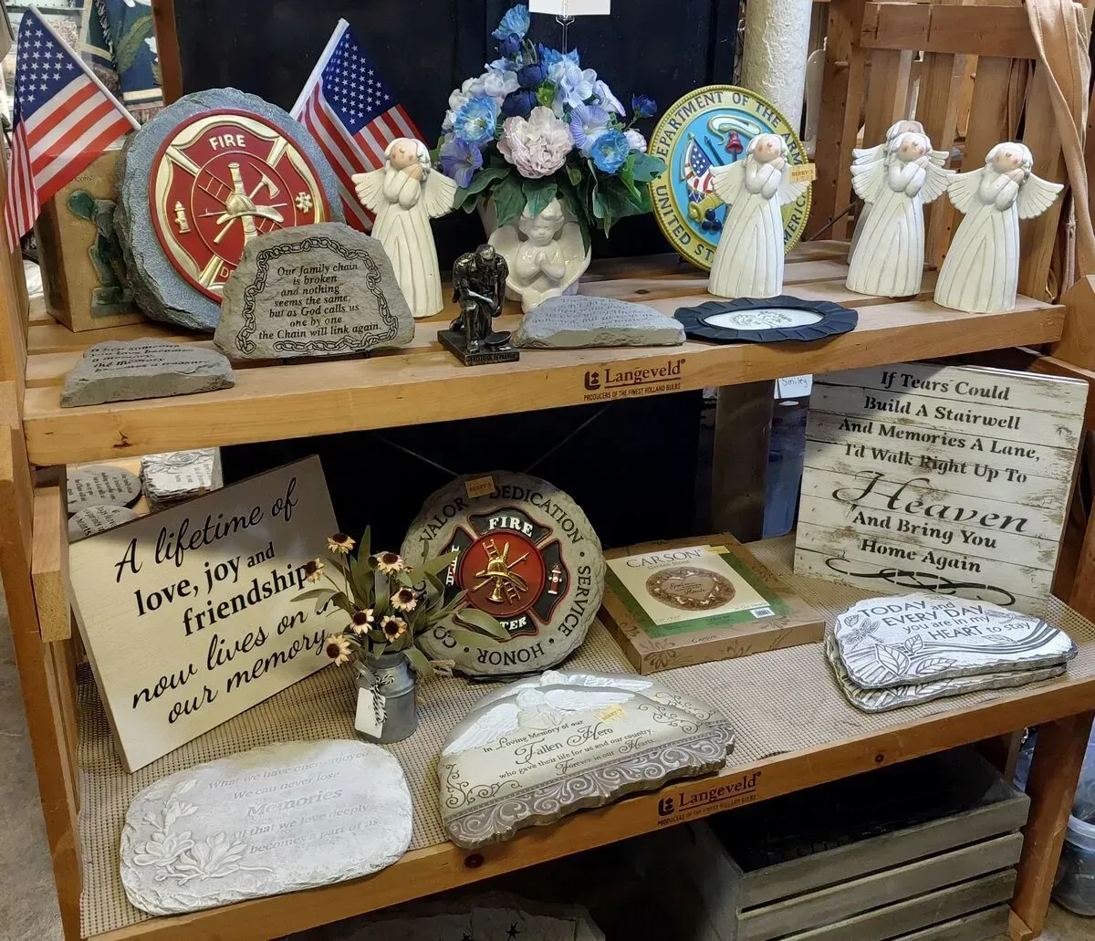 Wooden shelves display memorial stones, figurines, and flags.
