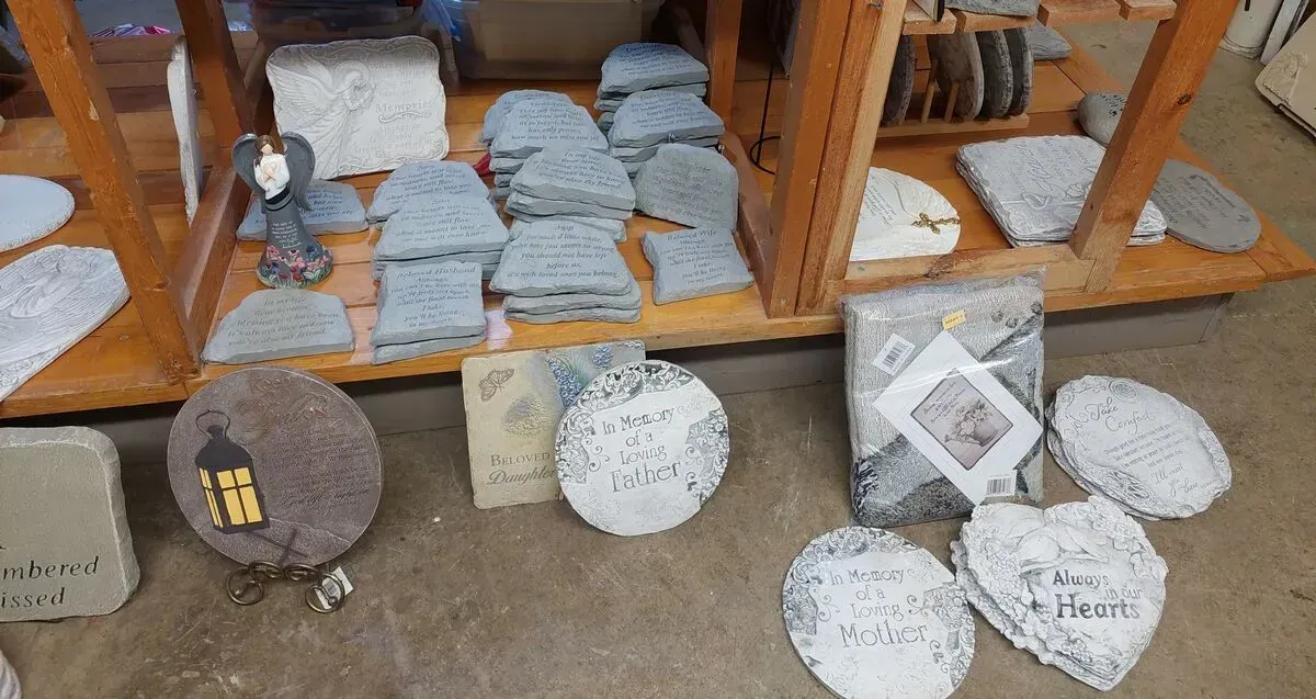 Stones with engraved words on a wooden shelf in a store. Some are heart-shaped or round.