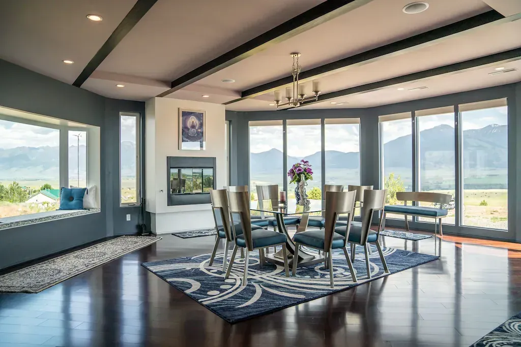 Dining room with round table, chairs, and large windows. Dining room with round table, chairs, and large windows.