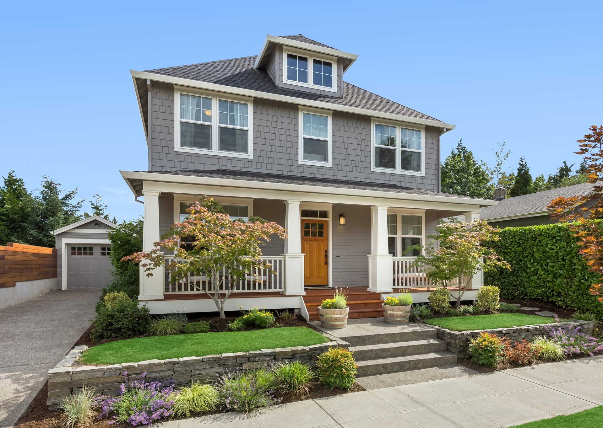 Gray two-story house with a porch, yellow door, and detached garage.