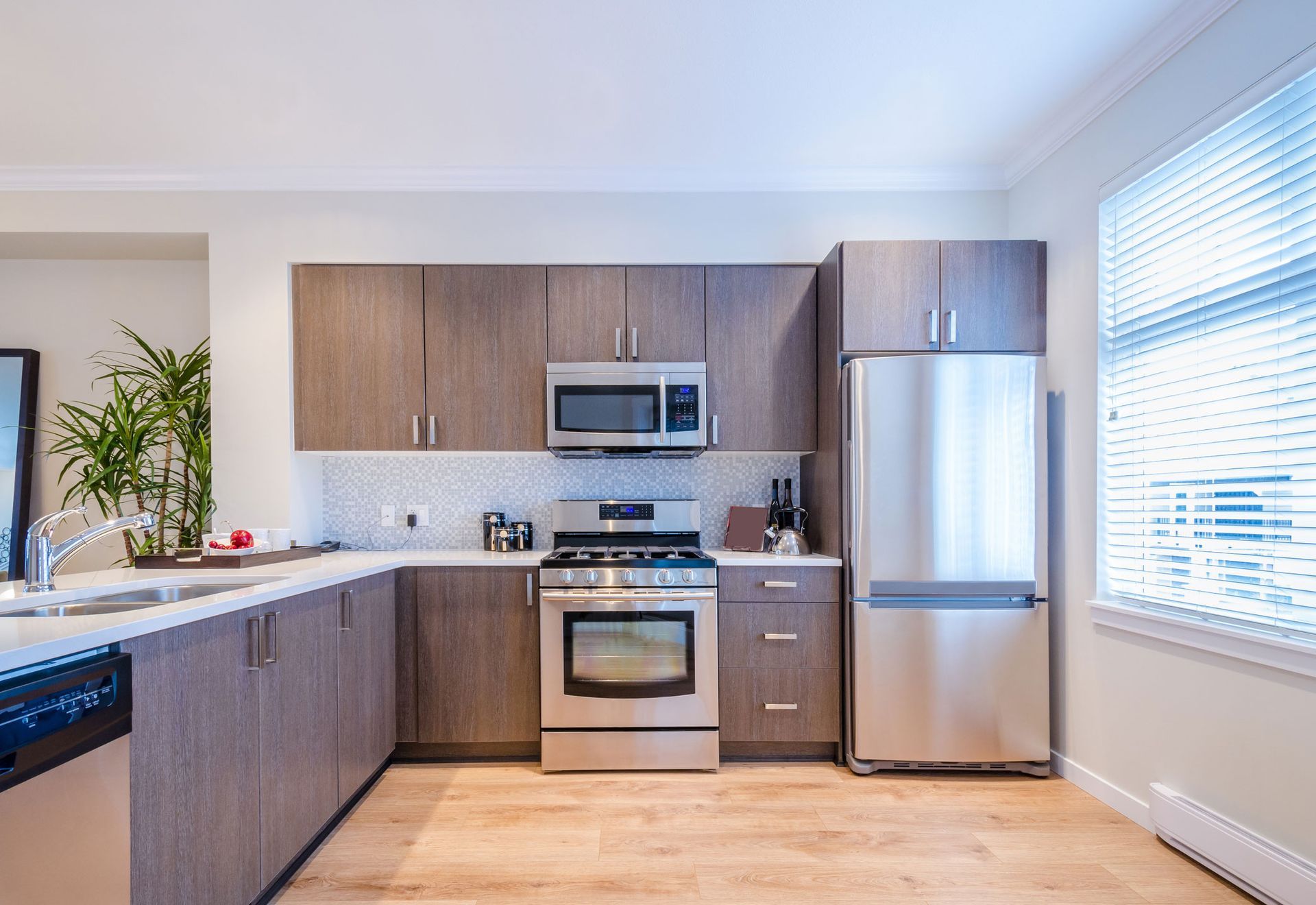 Modern kitchen with wood cabinets, stainless steel appliances, and a window with blinds.