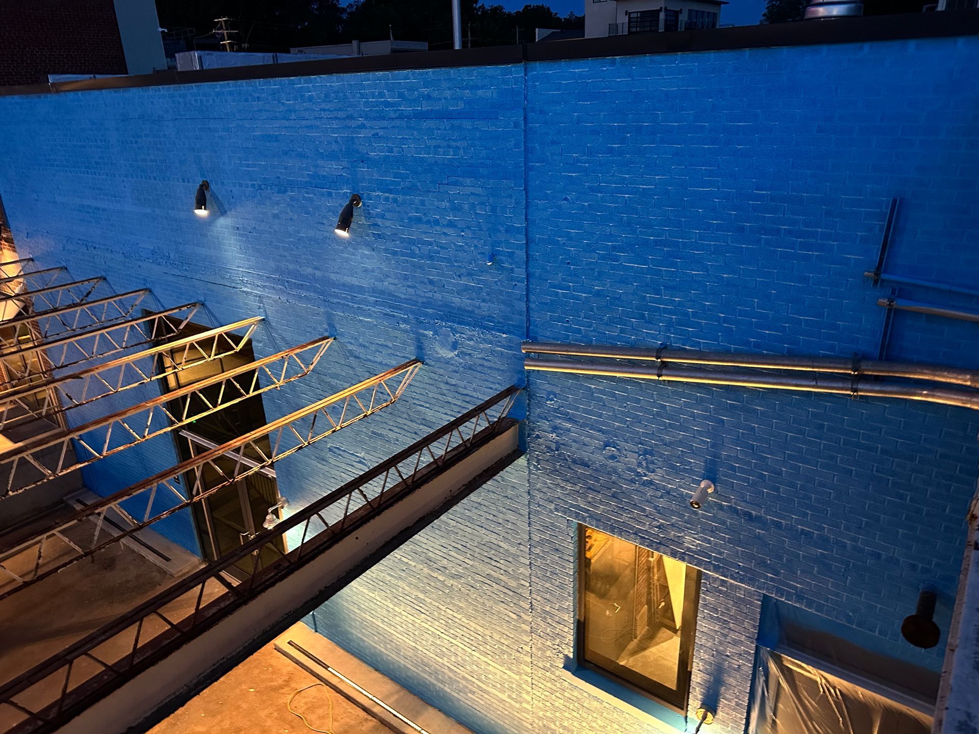 Two men are painting a wall from a rope.