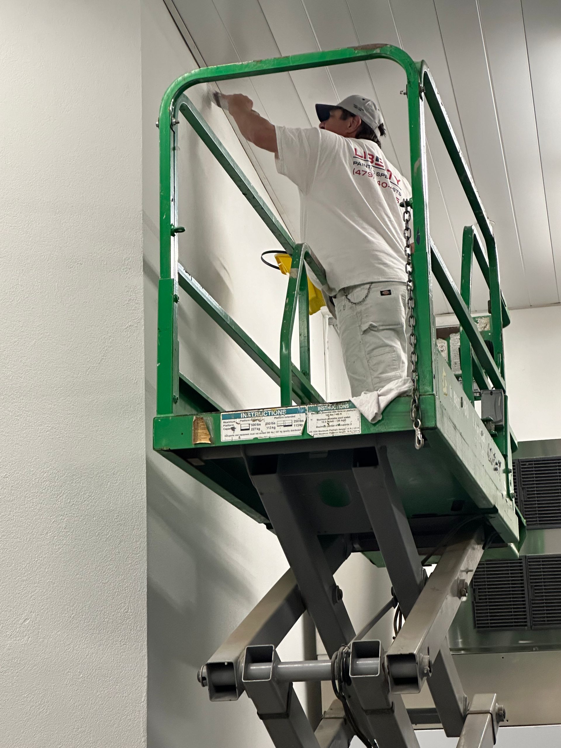 A person is painting a wall with a paint roller.
