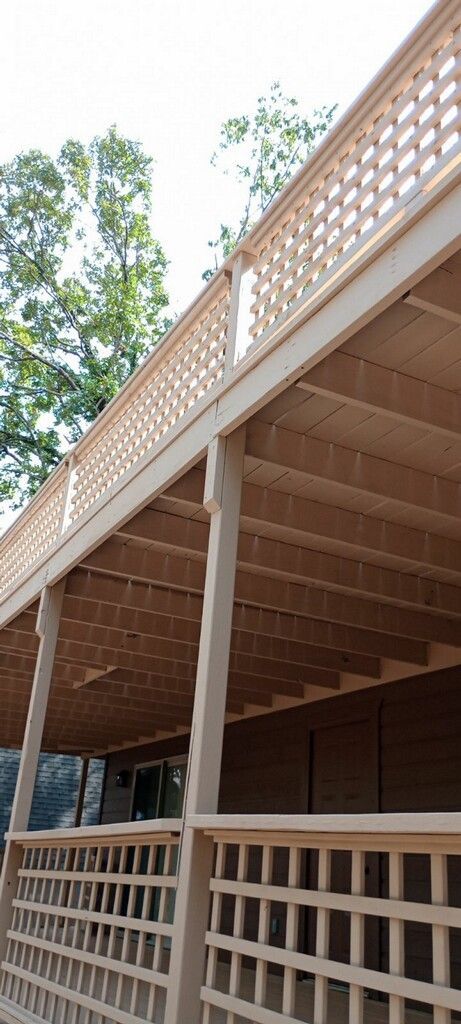 A man is painting a wooden deck with a brush.