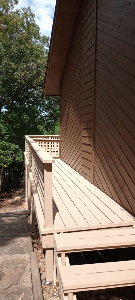 A person is painting a wooden deck with a brush.