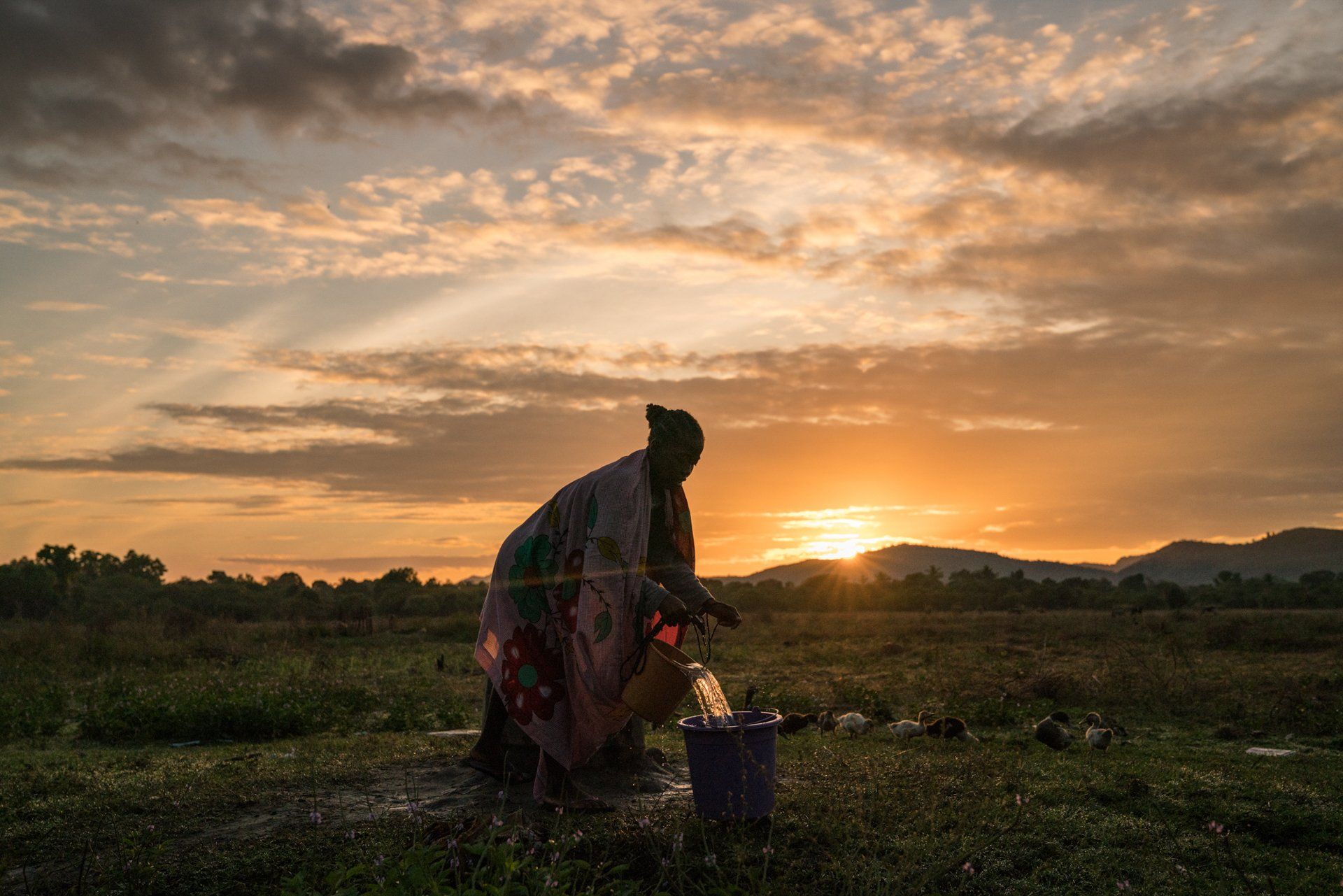 A woman pours water in Madagascar at sunset