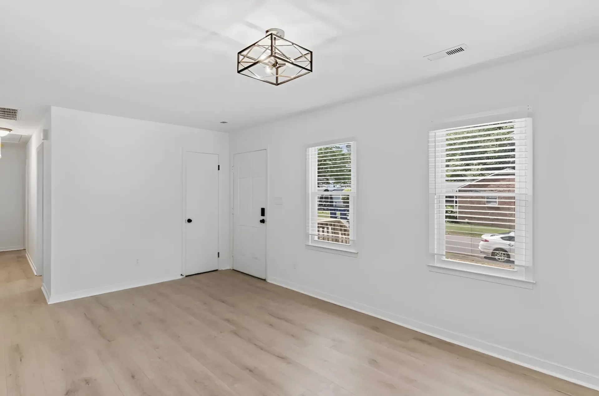 Woman in straw hat smiles, holding wine glass near a lake.