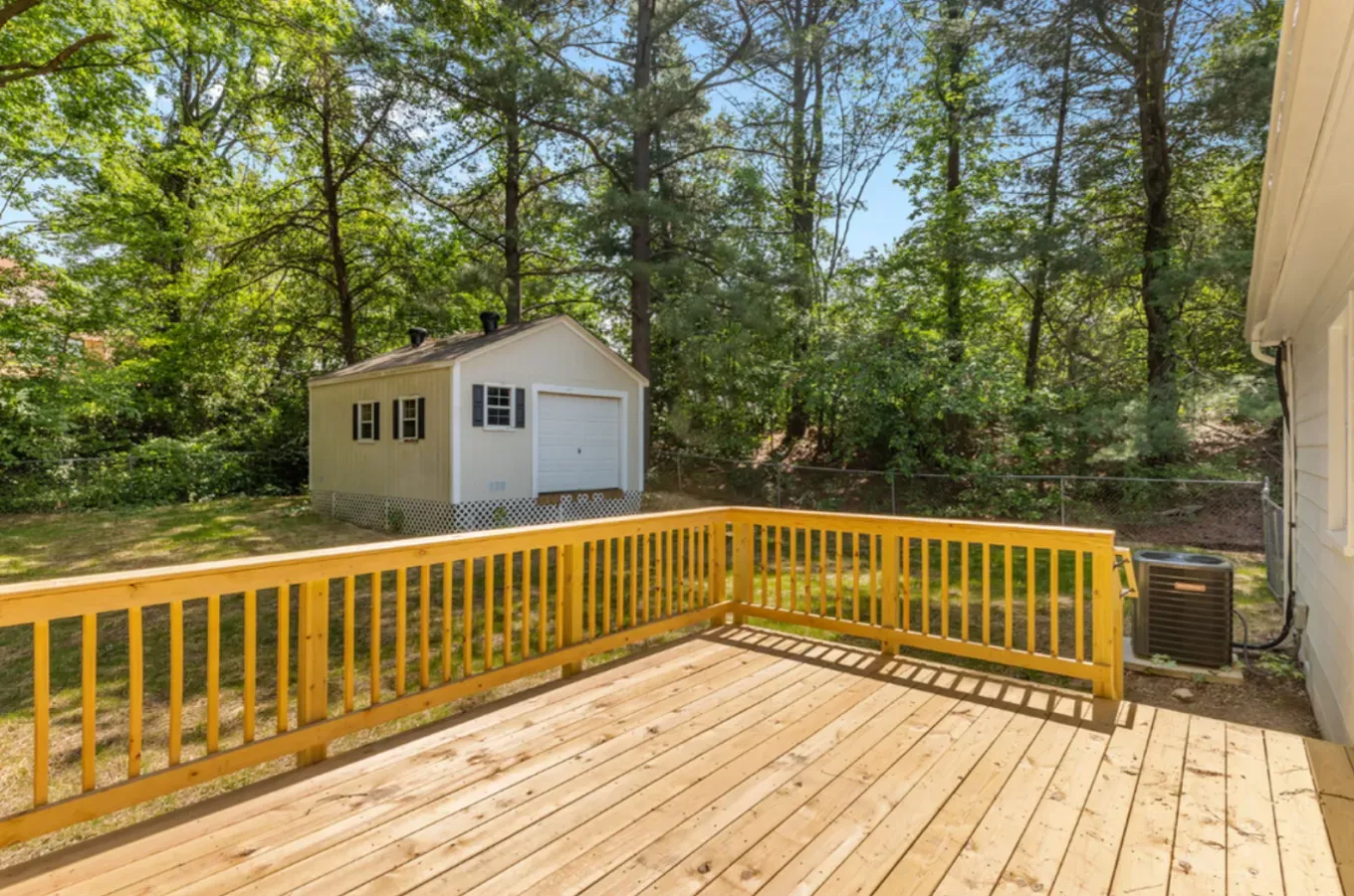 Woman in straw hat smiles, holding wine glass near a lake.
