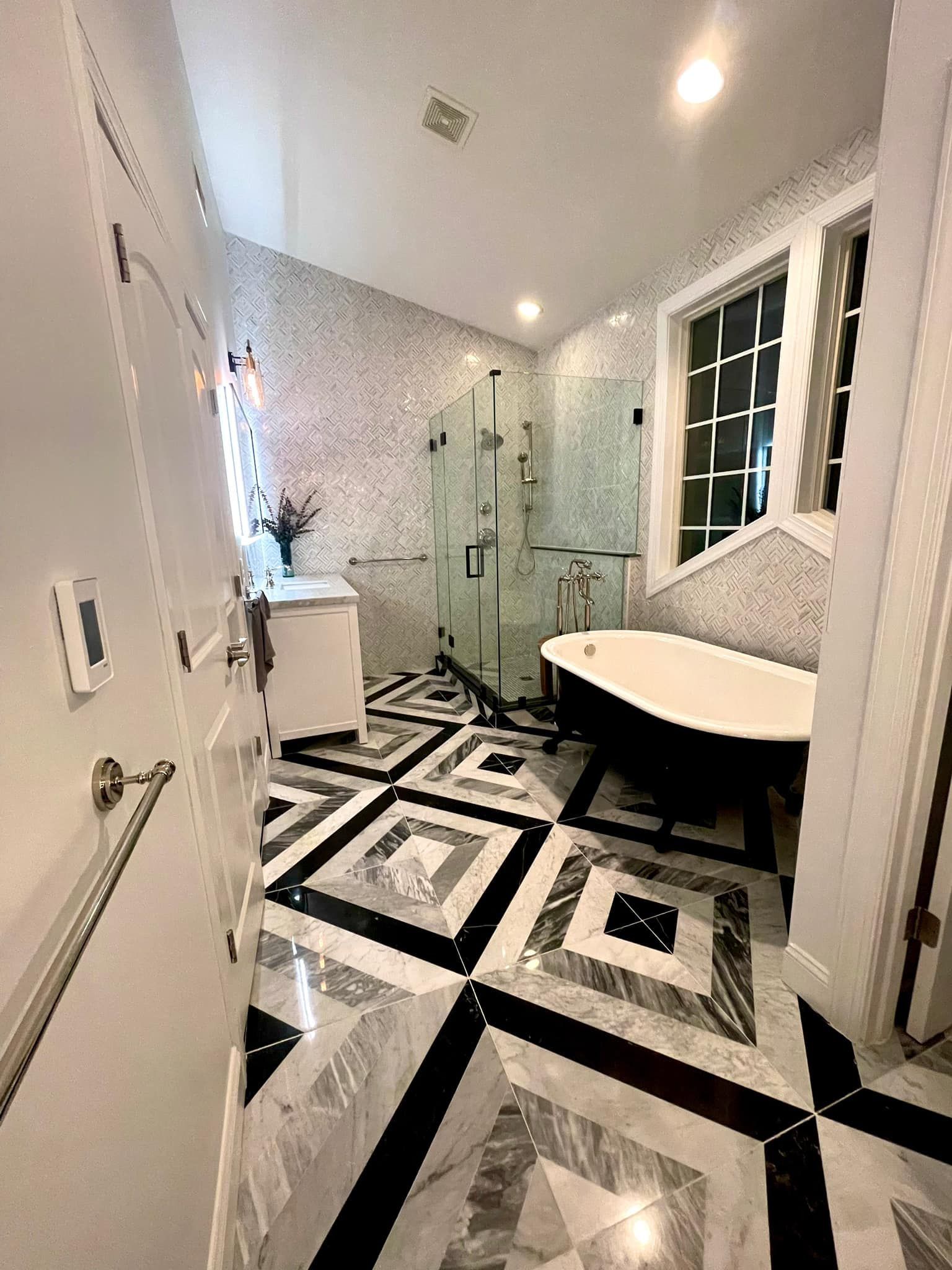 A modern luxury bathroom with a black-and-white patterned tile floor, a soaking tub, and a glass-enclosed shower.