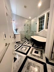 A modern luxury bathroom with a black-and-white patterned tile floor, a soaking tub, and a glass-enclosed shower.