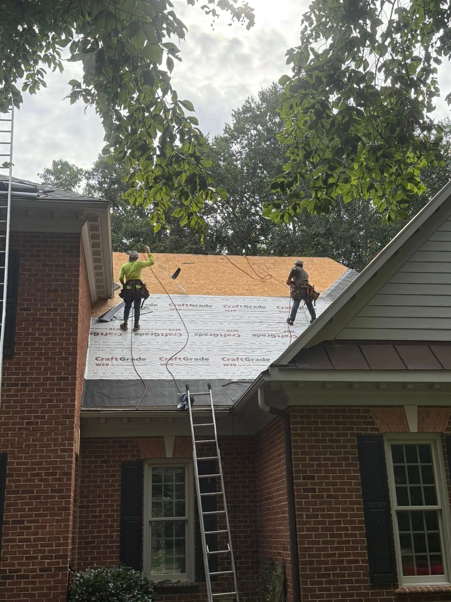Woman in straw hat smiles, holding wine glass near a lake.