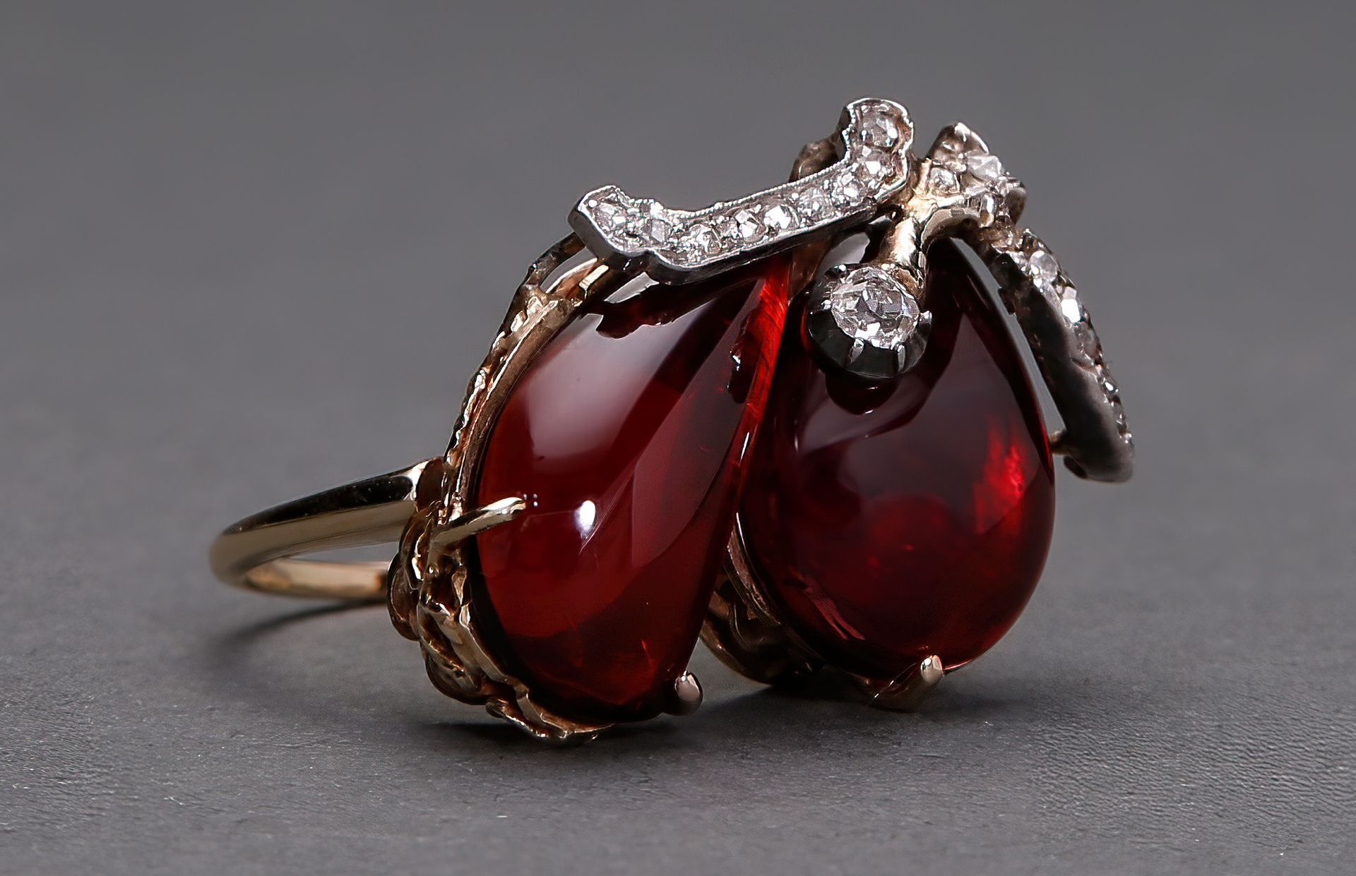 A gold ring with two red stones and diamonds
