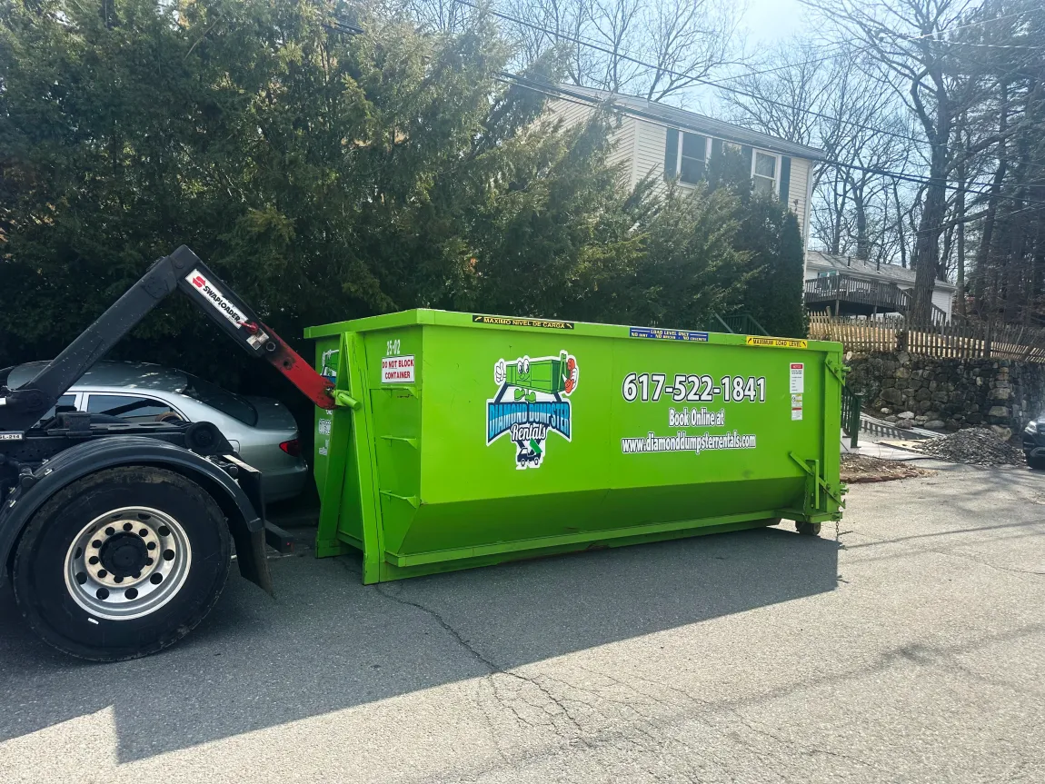 A green dumpster is sitting next to a truck in a parking lot.