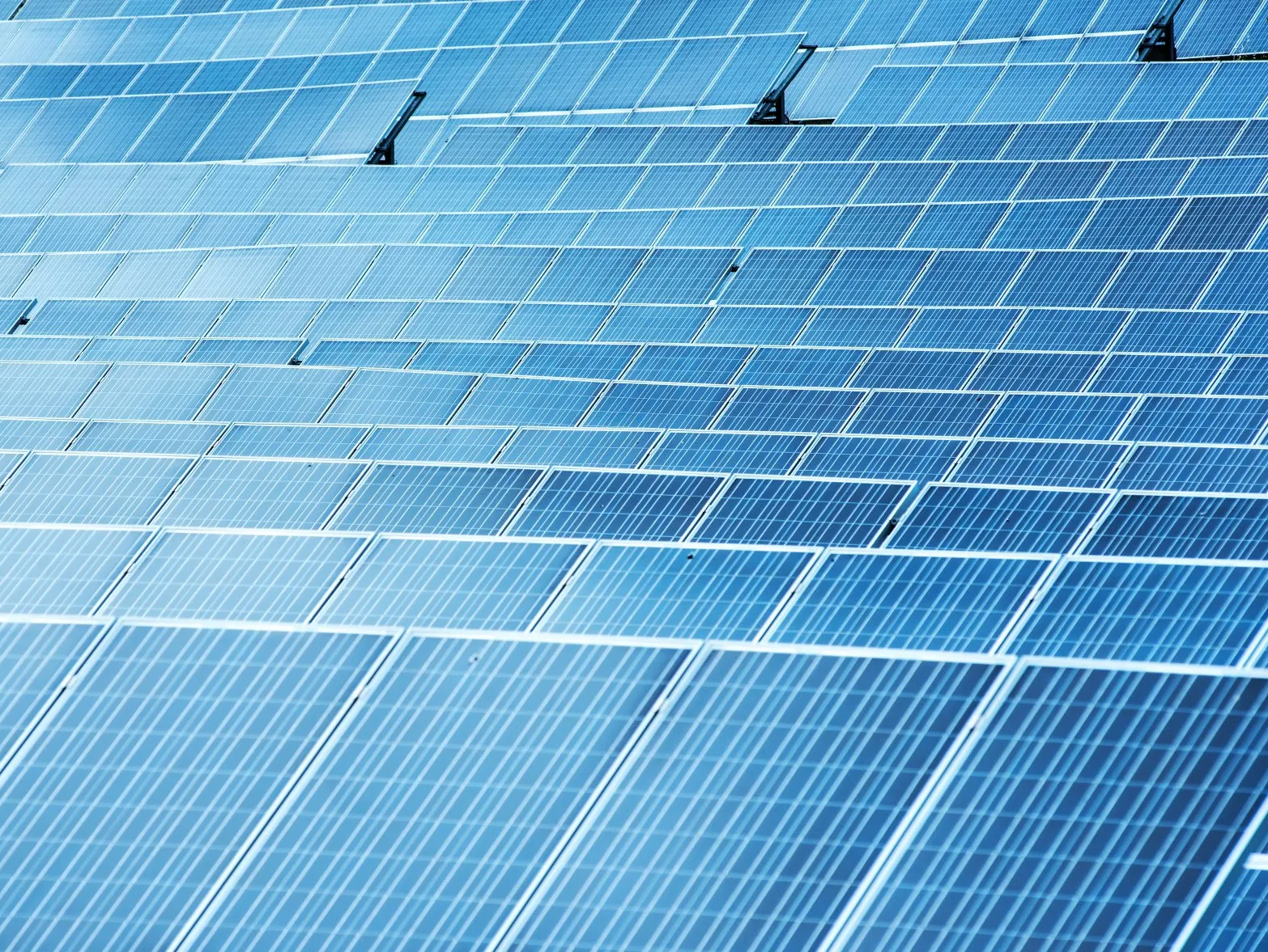 A row of blue solar panels sitting on top of a roof.