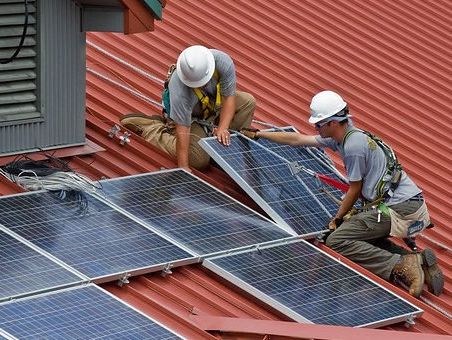 Two men are installing solar panels on the roof of a building.