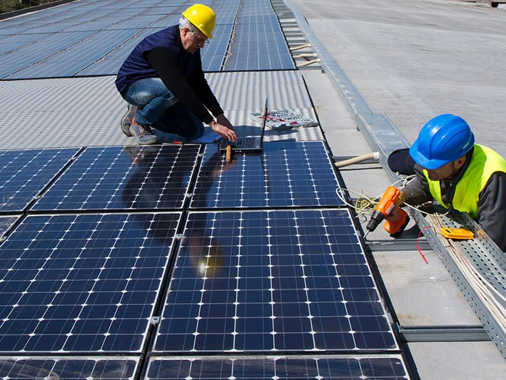 Two men are installing solar panels on a roof