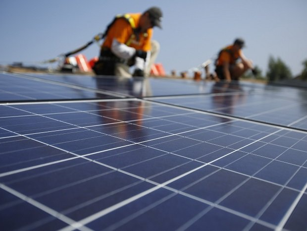 Two men are working on solar panels on a roof
