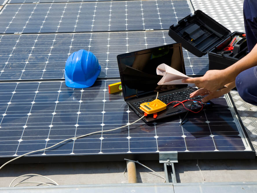 A person is working on a laptop on top of a solar panel.