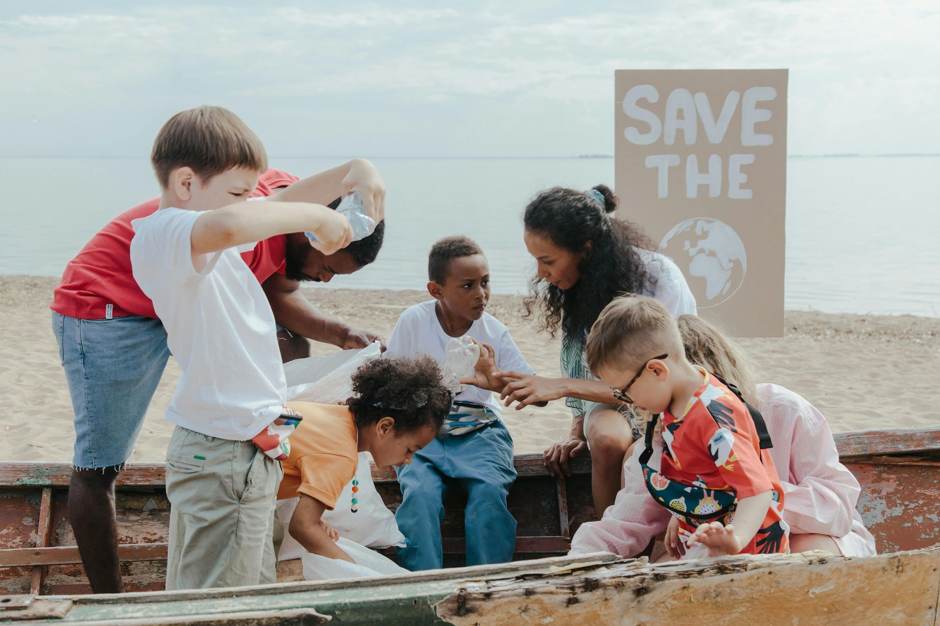 A group of children are sitting on a boat on the beach.