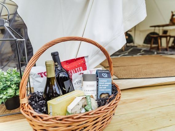 A wicker basket filled with food and wine is sitting on a wooden floor.
