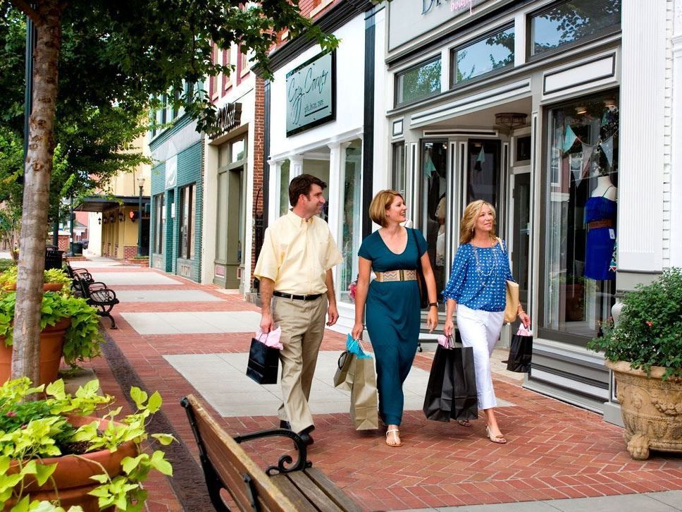 A man and two women are walking down a sidewalk with shopping bags.