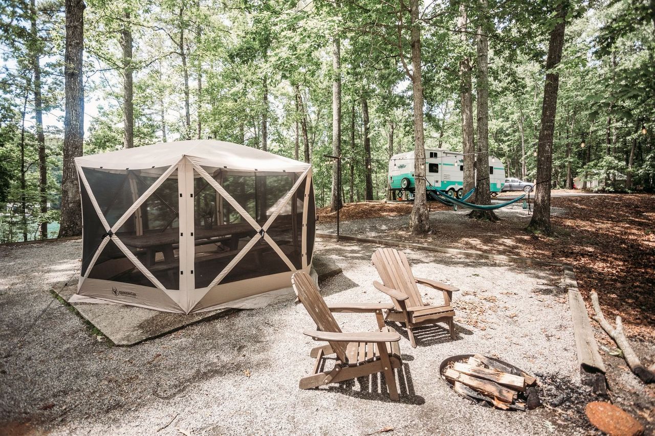 There is a tent and chairs in the middle of the woods.