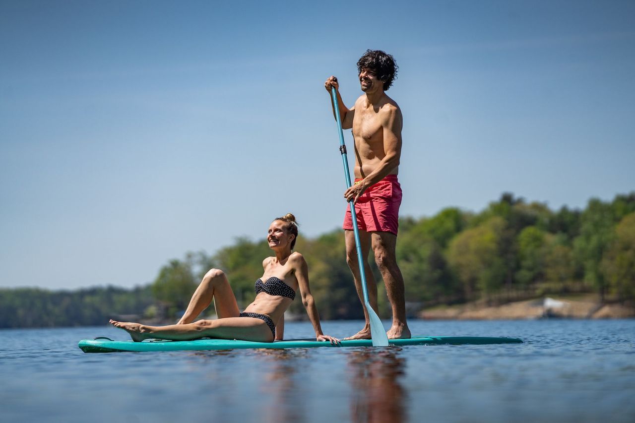 A man and a woman are riding a paddle board on a lake.