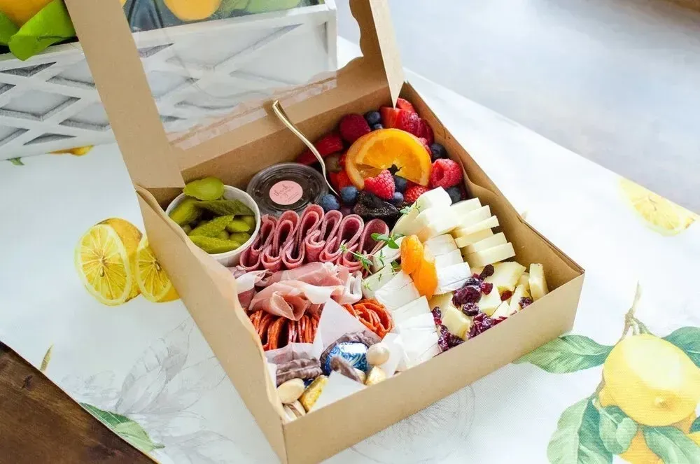 A cardboard box filled with food and fruit is sitting on a table.