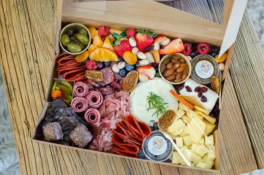 A box filled with lots of different types of food is sitting on a wooden table.