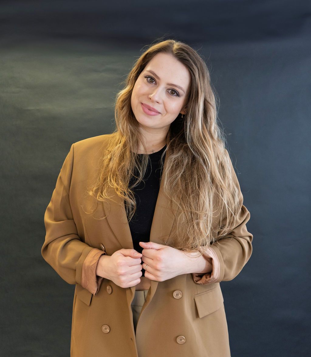 A woman is wearing a brown blazer and a black shirt.