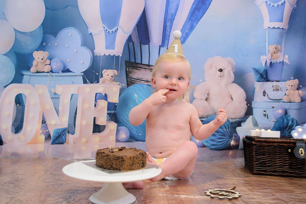 A baby is sitting on the floor eating a cake.