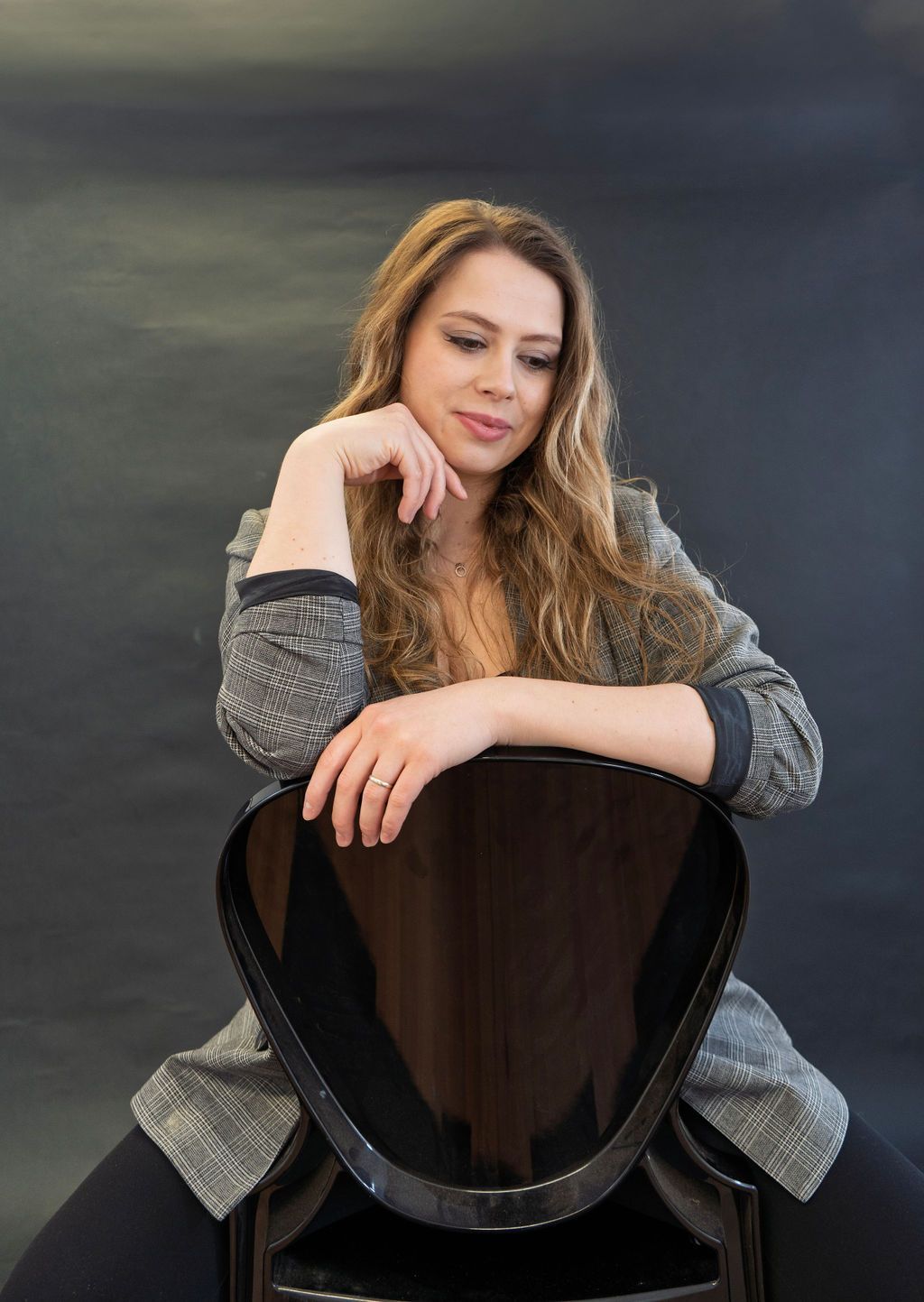 A woman is sitting on a chair with her hand on her chin.