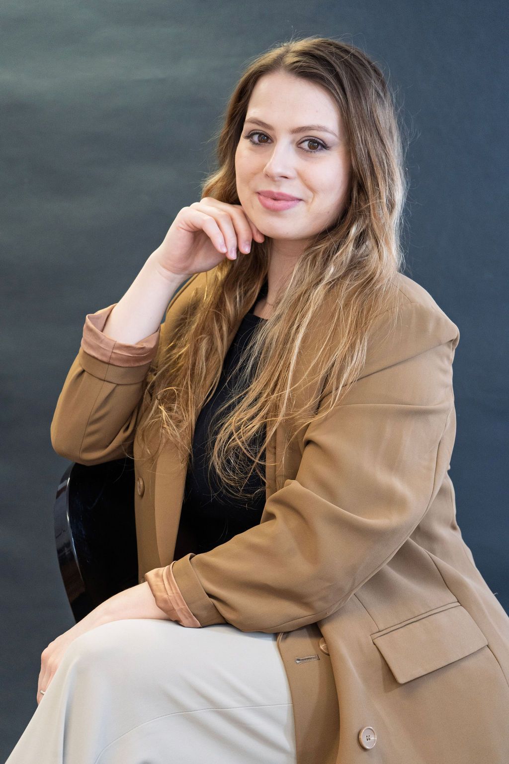 A woman is sitting in a chair with her hand on her chin.
