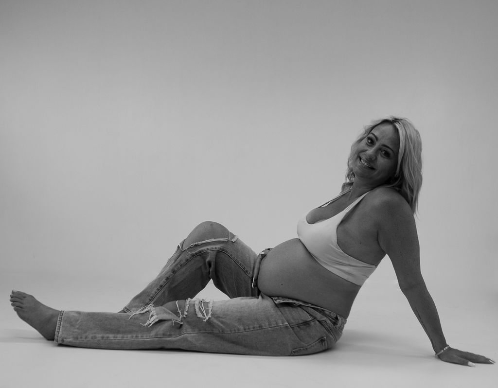 A black and white photo of a pregnant woman laying on the floor.