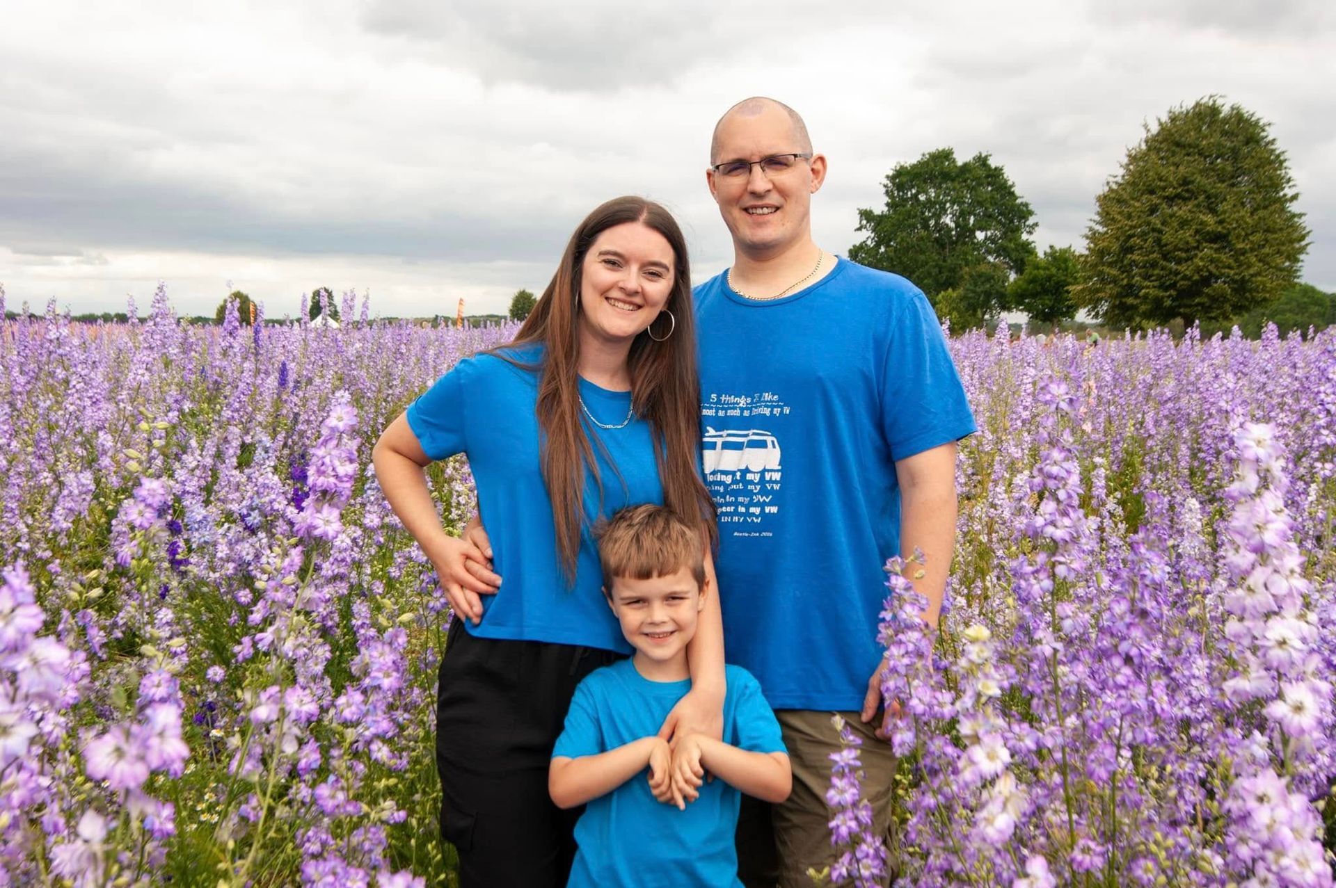 A family is posing for a picture in a field of purple flowers.