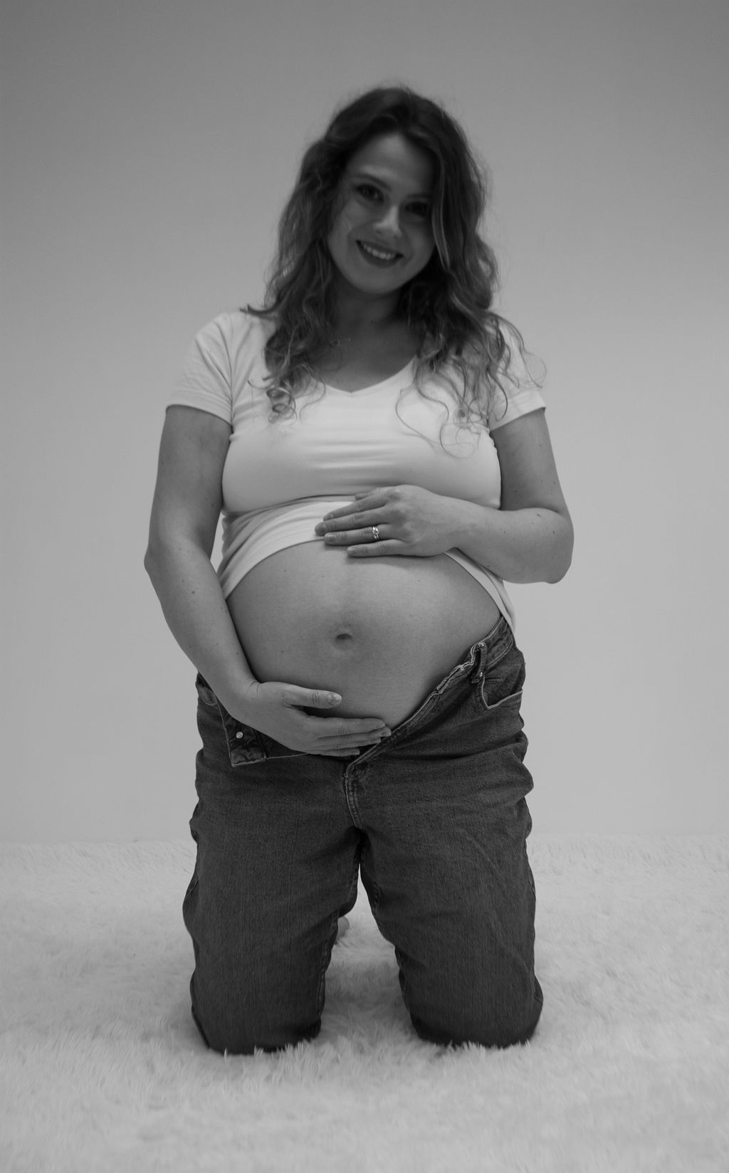 A pregnant woman is kneeling down and holding her belly.