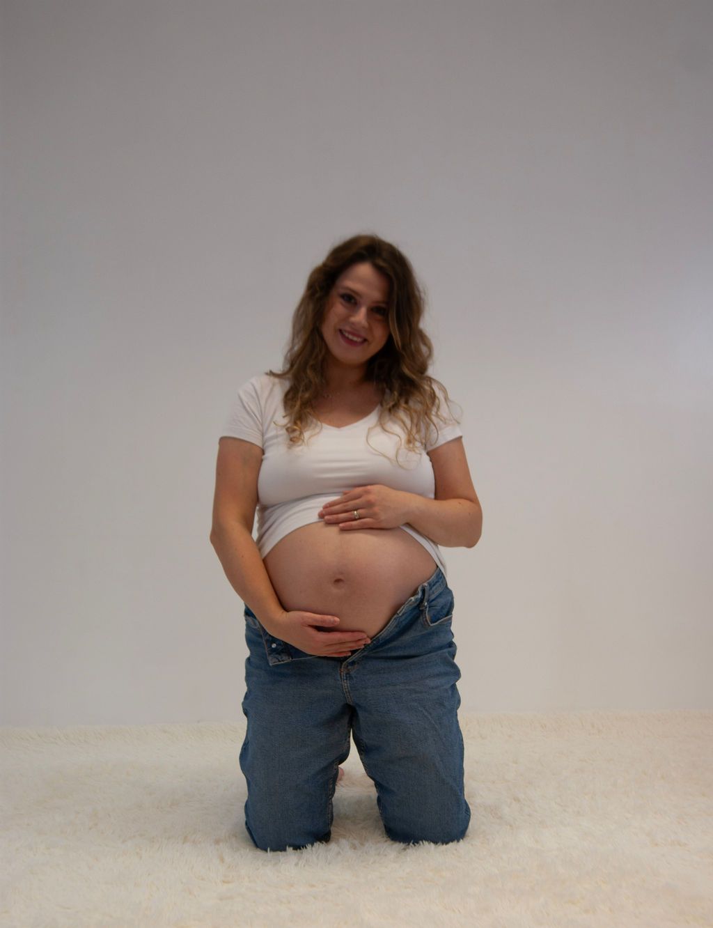 A pregnant woman is kneeling down and holding her belly