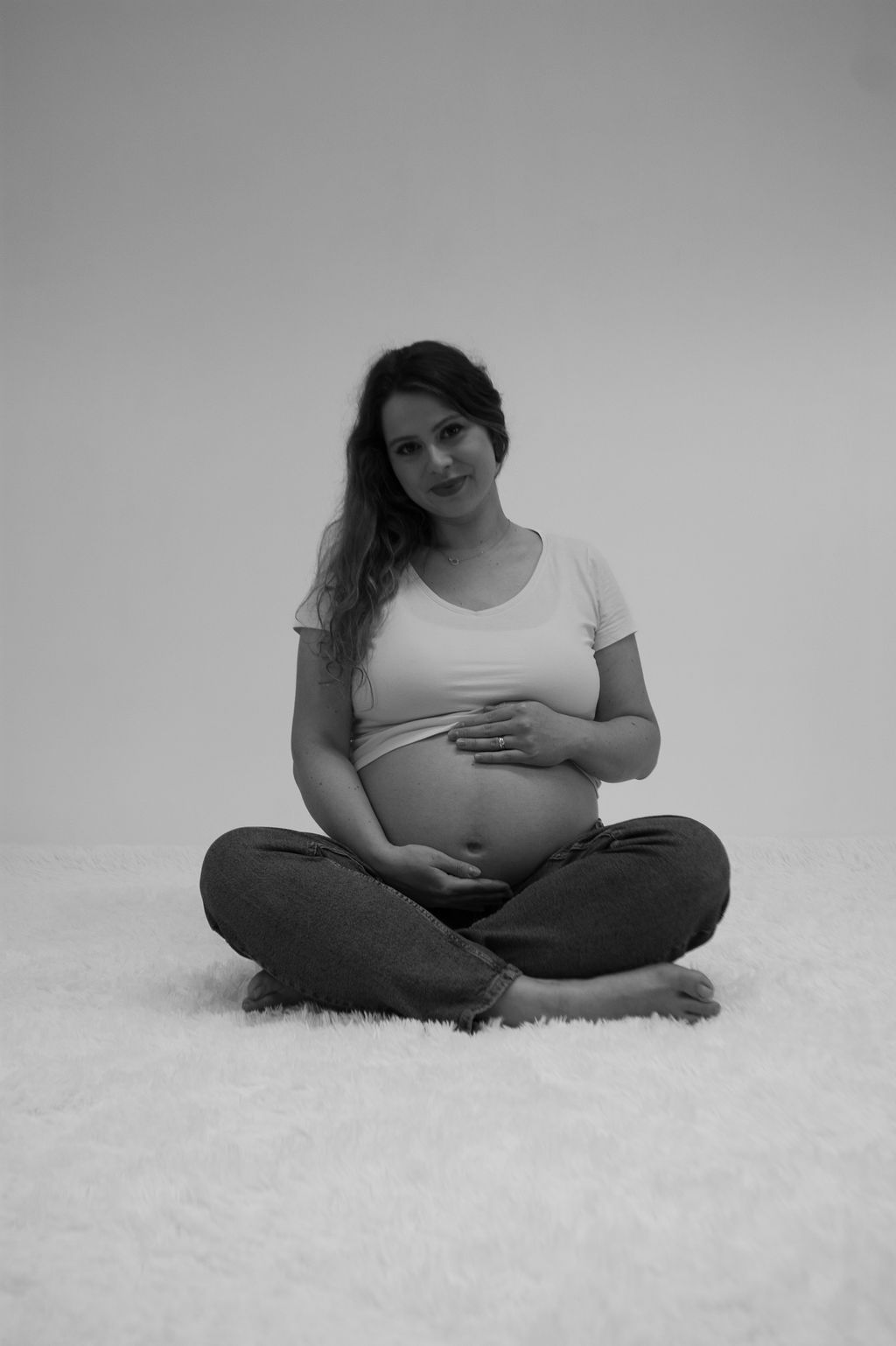 A pregnant woman is sitting on the floor holding her belly.