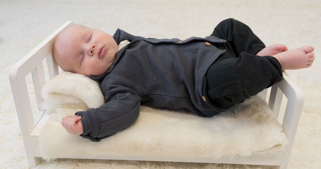 A baby is laying in a small white bed
